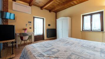 Une chambre à coucher comprenant un lit, un bureau, une chaise, un téléviseur et une armoire.