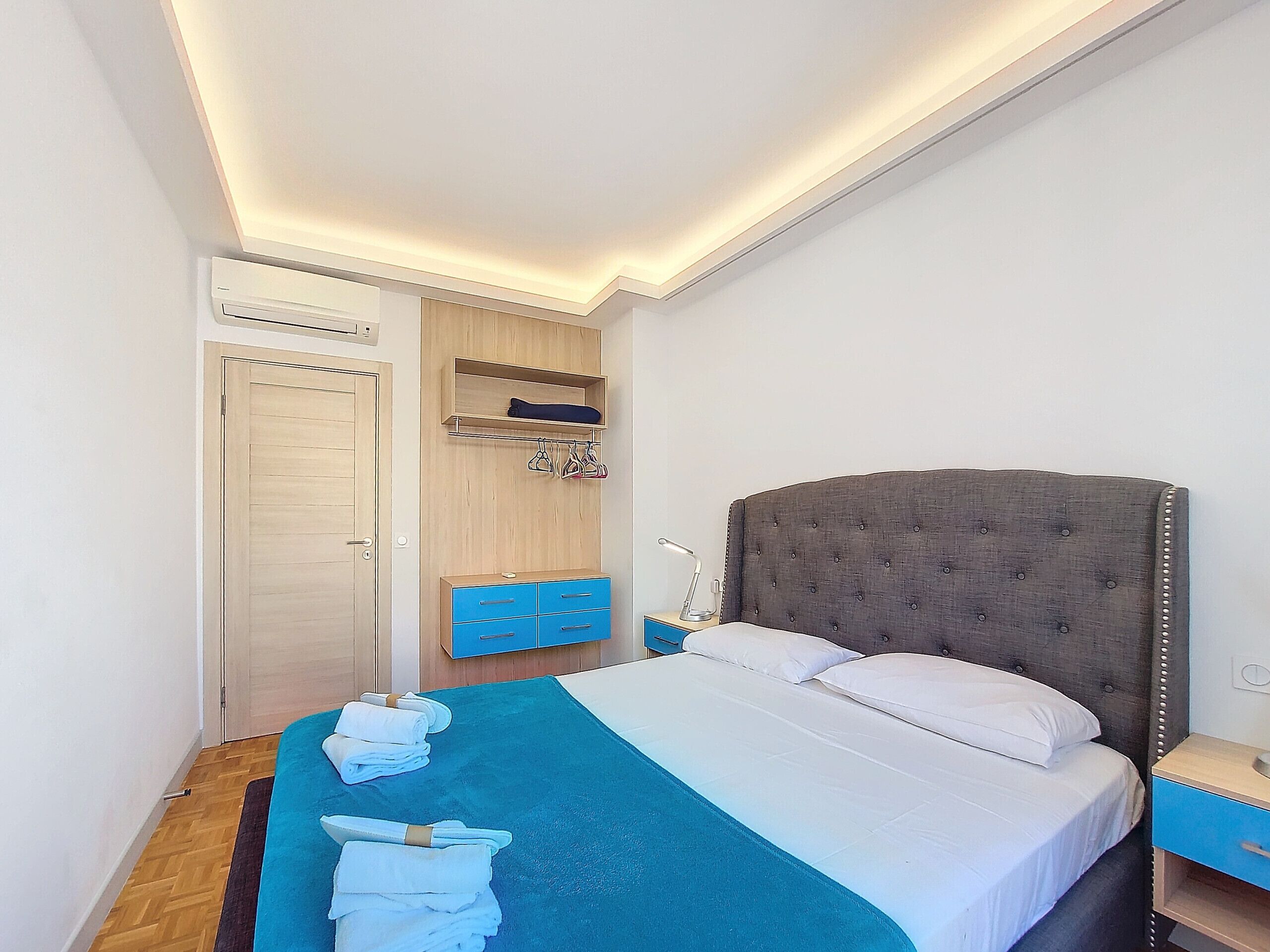 A bedroom with a bed, a bedside table, a wardrobe, a hanging rack, and a ceiling light.