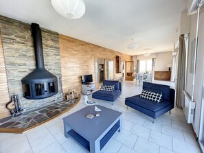 A modern living room with a stone fireplace, two sofas, a coffee table, and a TV.