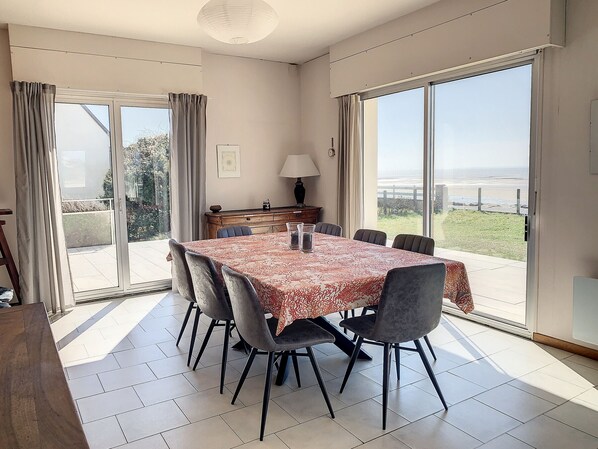 A dining area with a table set for six, a wooden sideboard, and a view of the outdoors.