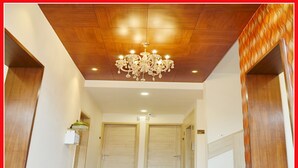 A hallway with a wooden ceiling and a chandelier. There are two doors at the end of the hallway. - Hotel Temple Inn (Amritsar)