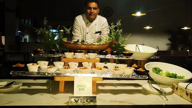 A buffet setup with labeled sections for salad bar and vegetarian options, featuring various dishes and utensils. - Hotel Temple Inn (Amritsar)