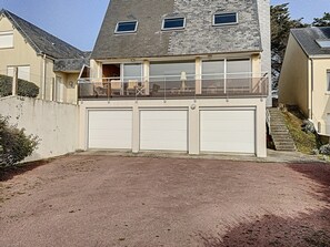 A two-story house with a balcony and three garage doors.