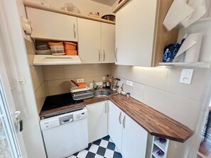A compact kitchen with white cabinets, a dishwasher, and a checkered floor.