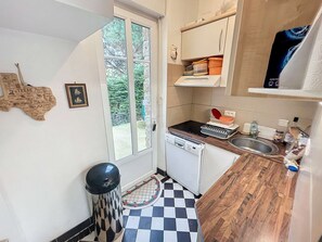 A compact kitchen with a dishwasher, a sink, and a window.