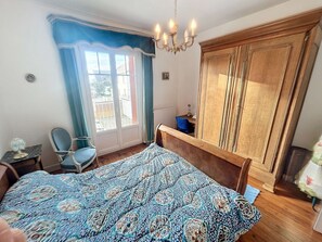 A bedroom with a large bed, a chair, a desk, and a wardrobe.