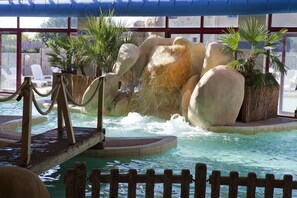 Un espace piscine agrémenté d’une cascade, de chaises longues et de plantes en pot.