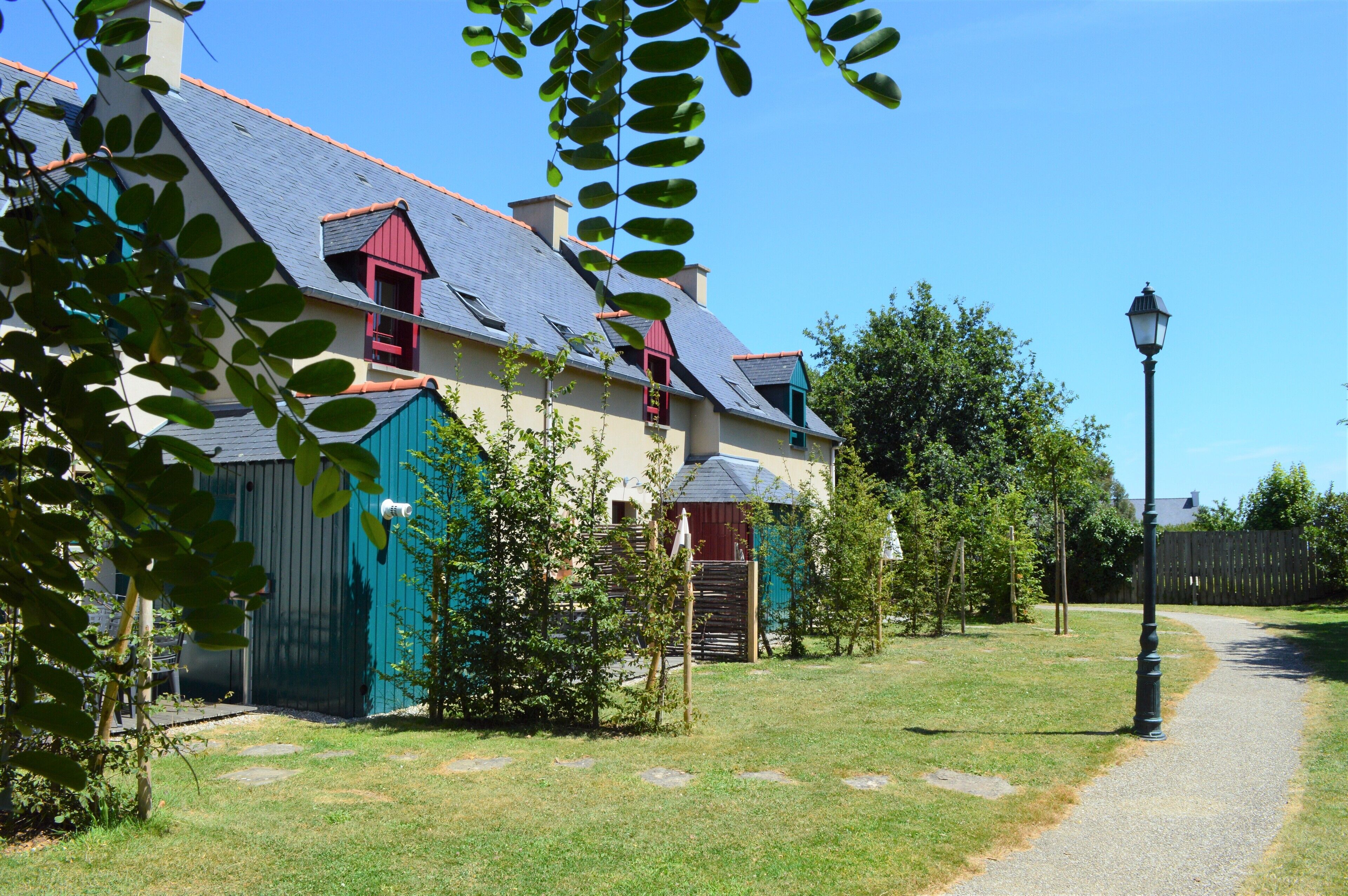 Une maison avec un toit en pente, une cheminée rouge et un chemin qui y mène.