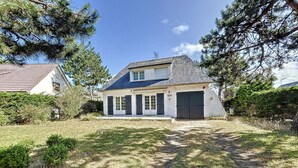 A two-story house with a sloped roof, a front porch, and a garage. - Beachside Villa with Garden, Free Wifi & BBQ – Close to Shops & Attractions (Jullouville)