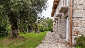 A stone pathway leading to a stone building with a balcony. - Eido do Carvalhoso (Arcos de Valdevez)