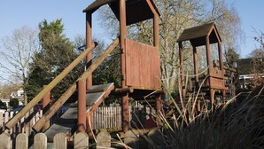 A wooden play structure with a slide and climbing elements.