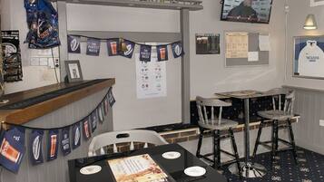 Eine Bar mit Theke, Hockstühlen und einem Fernseher.