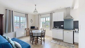 A modern kitchen with white cabinets, a built-in stove, and a window overlooking a garden. - Cozy Apartment 100m from Beach & Shops, Near Mont Saint-Michel (Jullouville)