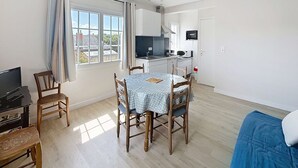 A compact living space with a dining area, kitchen, and a television. - Cozy Apartment 100m from Beach & Shops, Near Mont Saint-Michel (Jullouville)