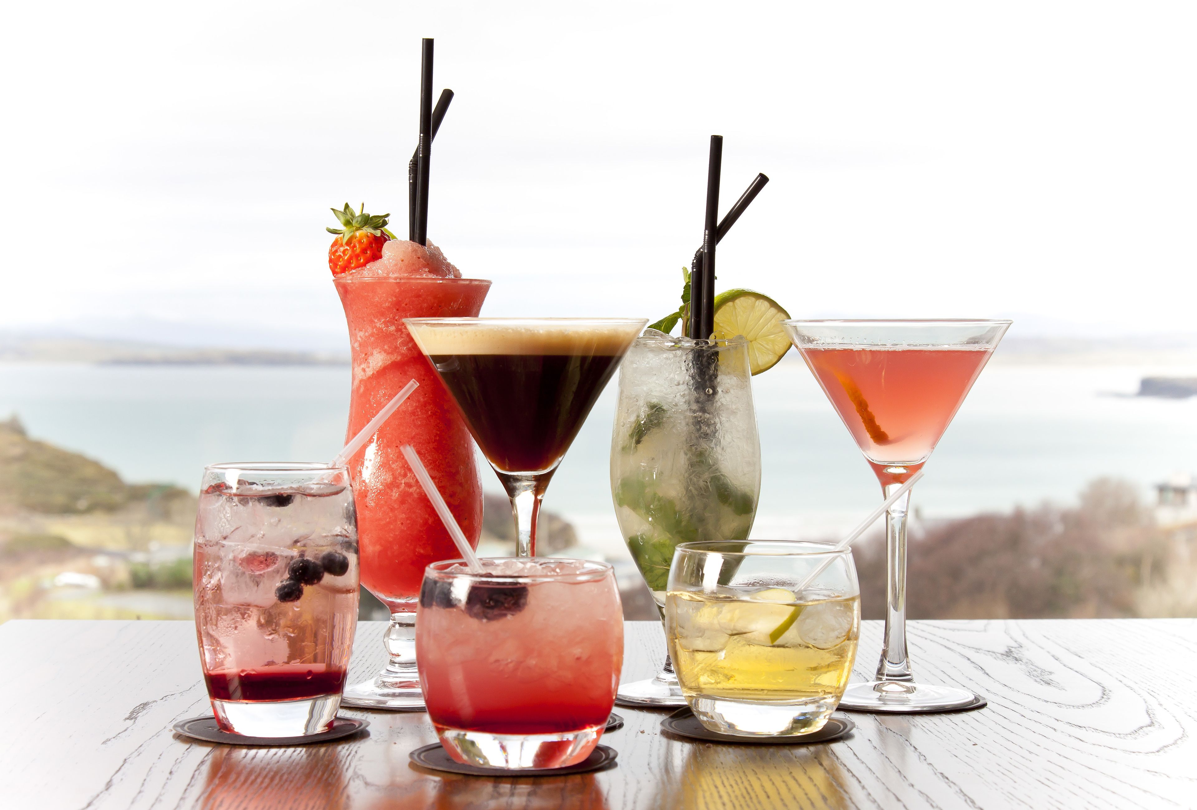 A variety of drinks on a table with a scenic view in the background.