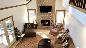A living room with a fireplace, sofas, a coffee table, and a TV mounted on the wall.