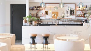 A bar area with stools, a counter, and shelves with bottles. - Hôtel Santateresa (Bonifacio)