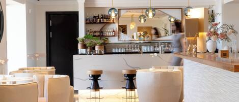 Zona de bar moderna con asientos, una barra repleta de botellas y un espejo grande.
