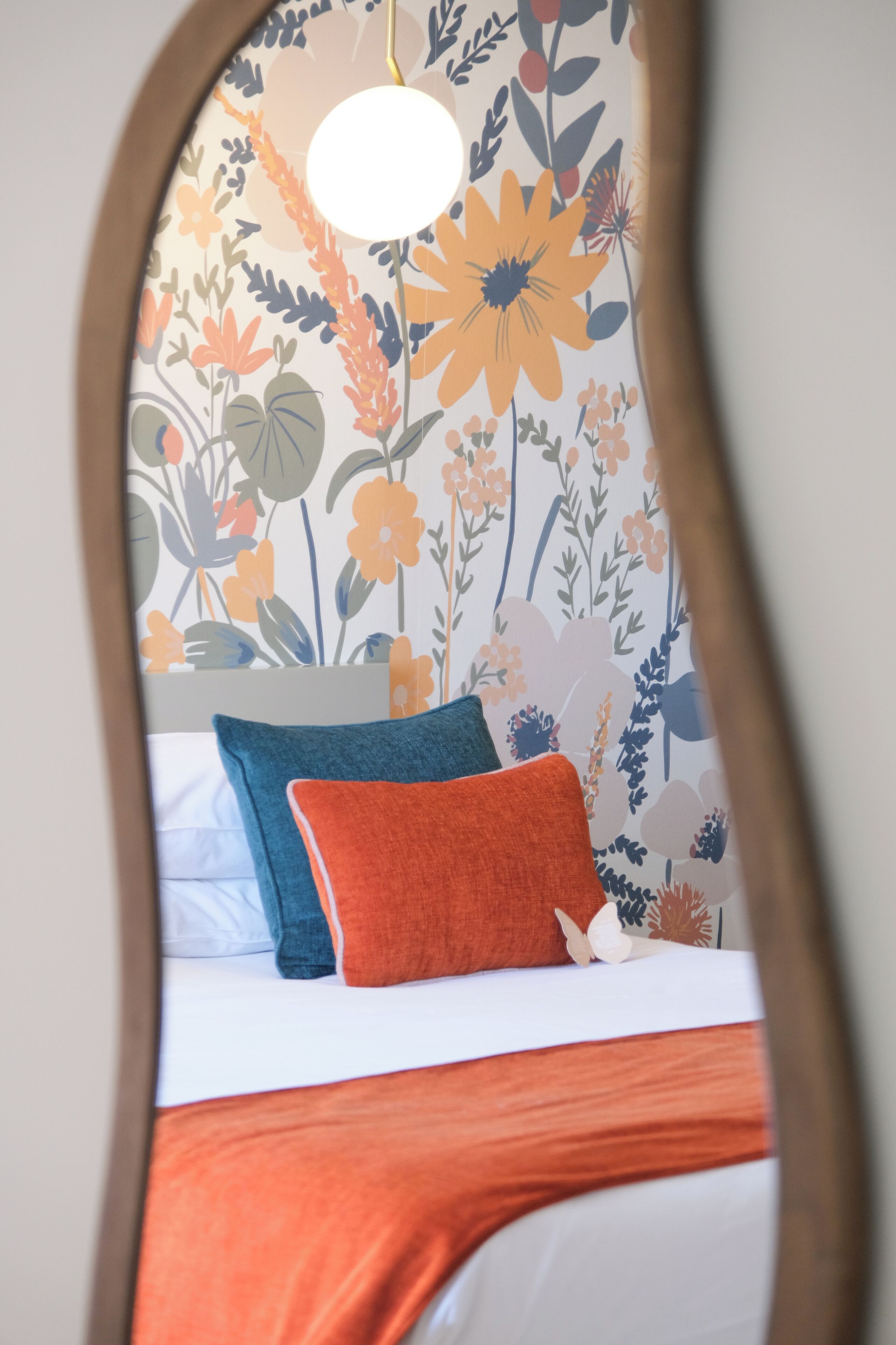 Cama com roupa de cama branca, um travesseiro azul e um travesseiro laranja.