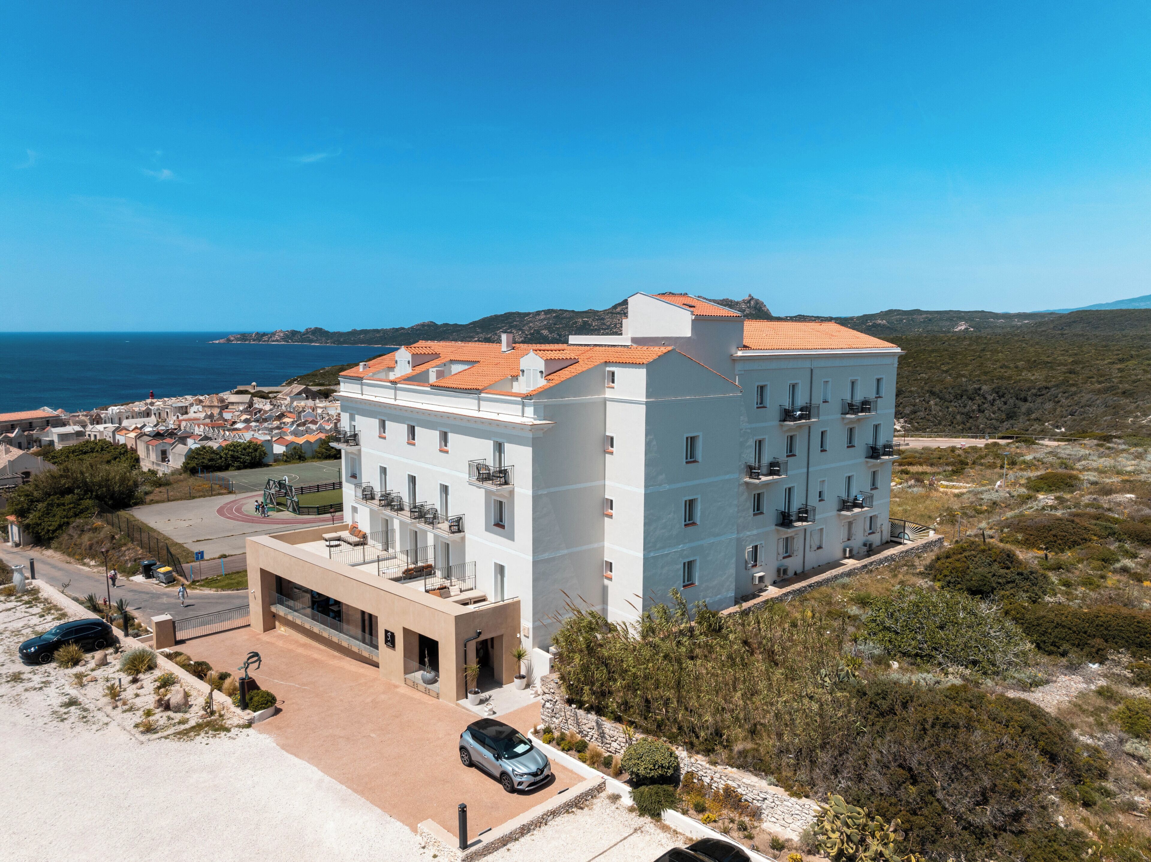 Um hotel com vários andares, varandas, área de estacionamento e vista para o mar.