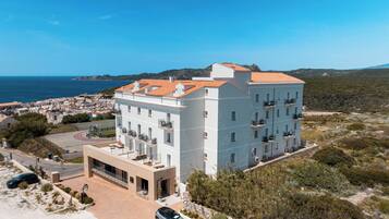 Un hôtel à plusieurs étages, doté de balcons, d’un parking et offrant une vue sur la mer.