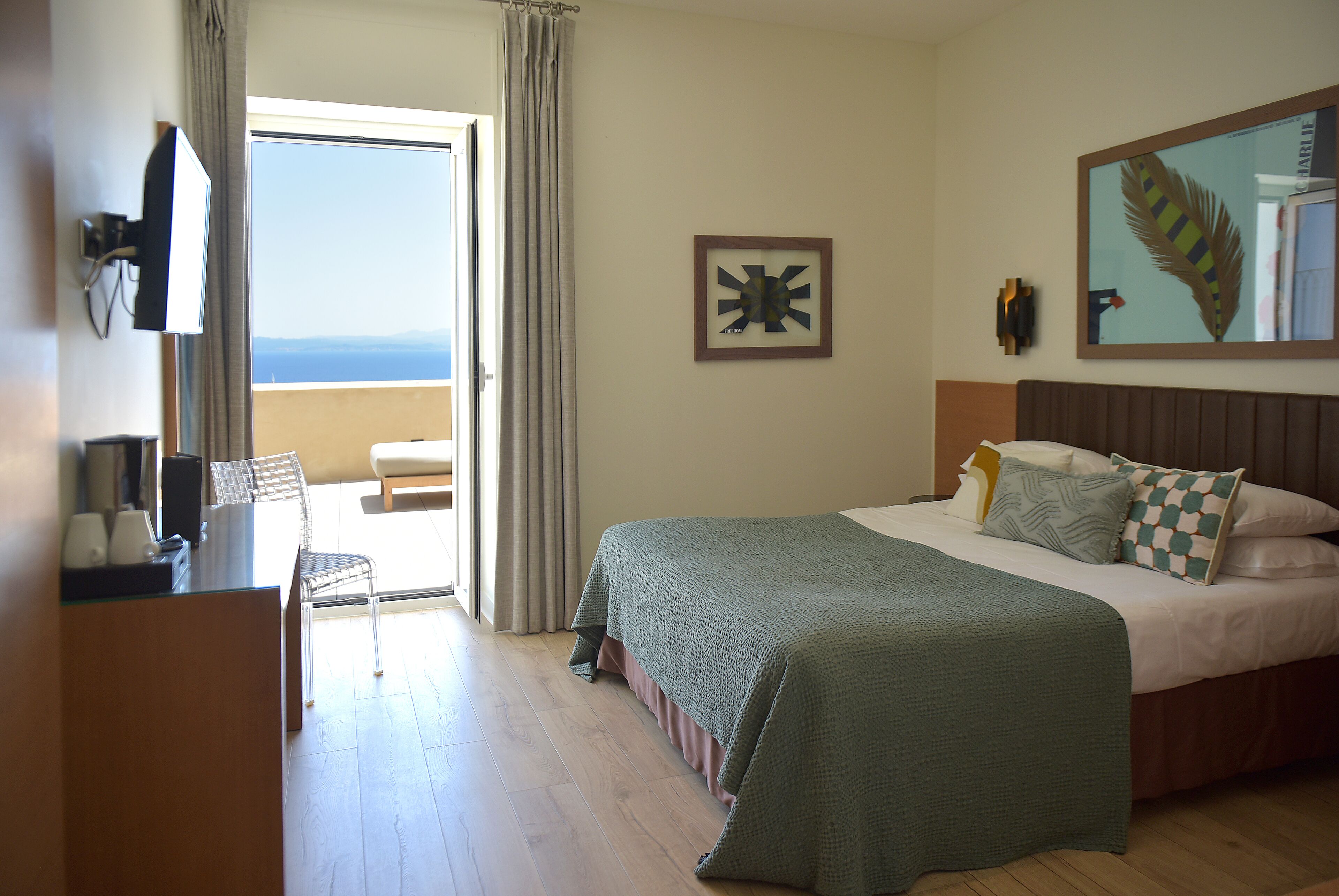 A hotel room with a bed, a desk with a chair, a television, and a view of the outdoors.