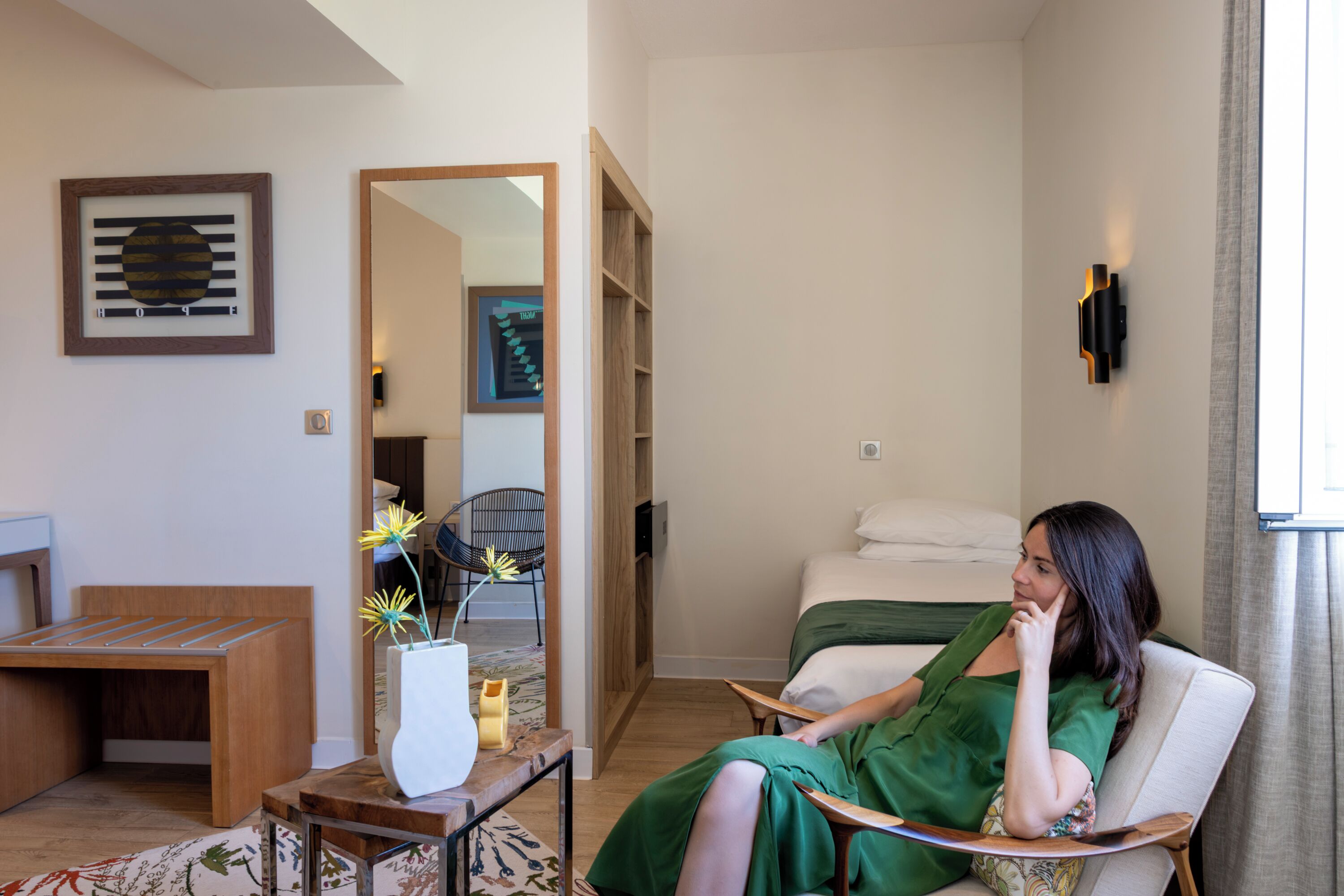 Une pièce comprenant un lit, une chaise, une table d’appoint en bois et un miroir.