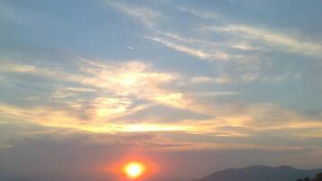 A sunset over a body of water with distant landforms and a clear sky.