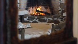 A stone fireplace with a fire burning inside, visible through a wooden-framed mirror. - Ktima Nikola (Karystos)