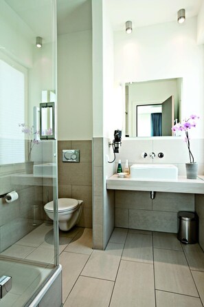 A modern bathroom with a glass shower enclosure, a white sink, and a large mirror. - Aspria Hannover Maschsee – Sport & Spa (Hannover)