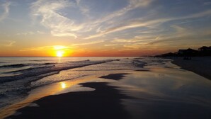 Ein Strand mit Sonnenuntergang, Wellen und wolkenlosem Himmel.