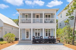 A two-story building with a front porch, a small garden, and a clear sky.