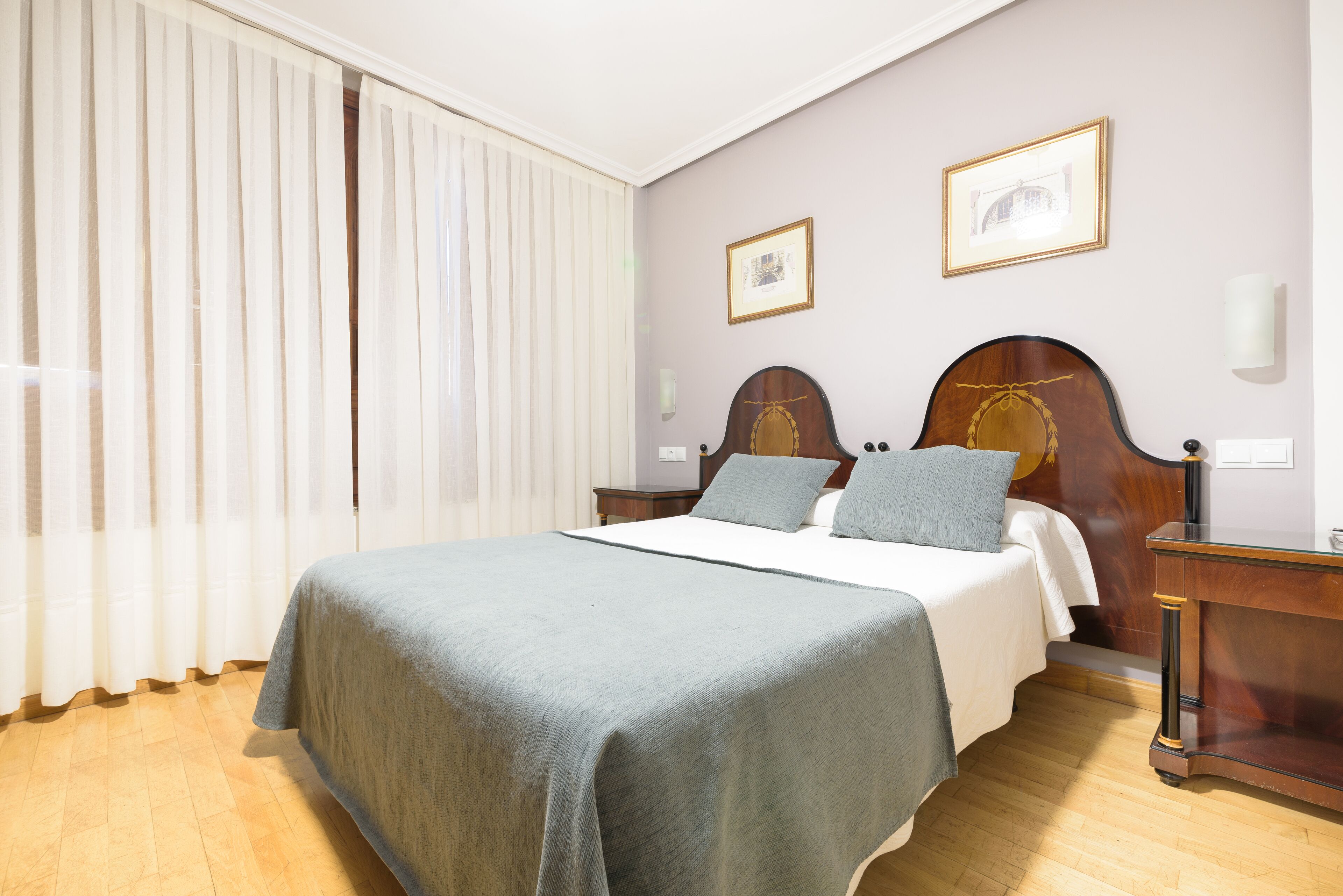 Een netjes ingerichte slaapkamer met een bed, nachtkastjes en een nachttafeltje.