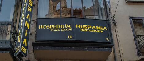 A building with a sign for 'HOSPEDIUM' and 'HISPANIA RESTAURANTE' on the facade.