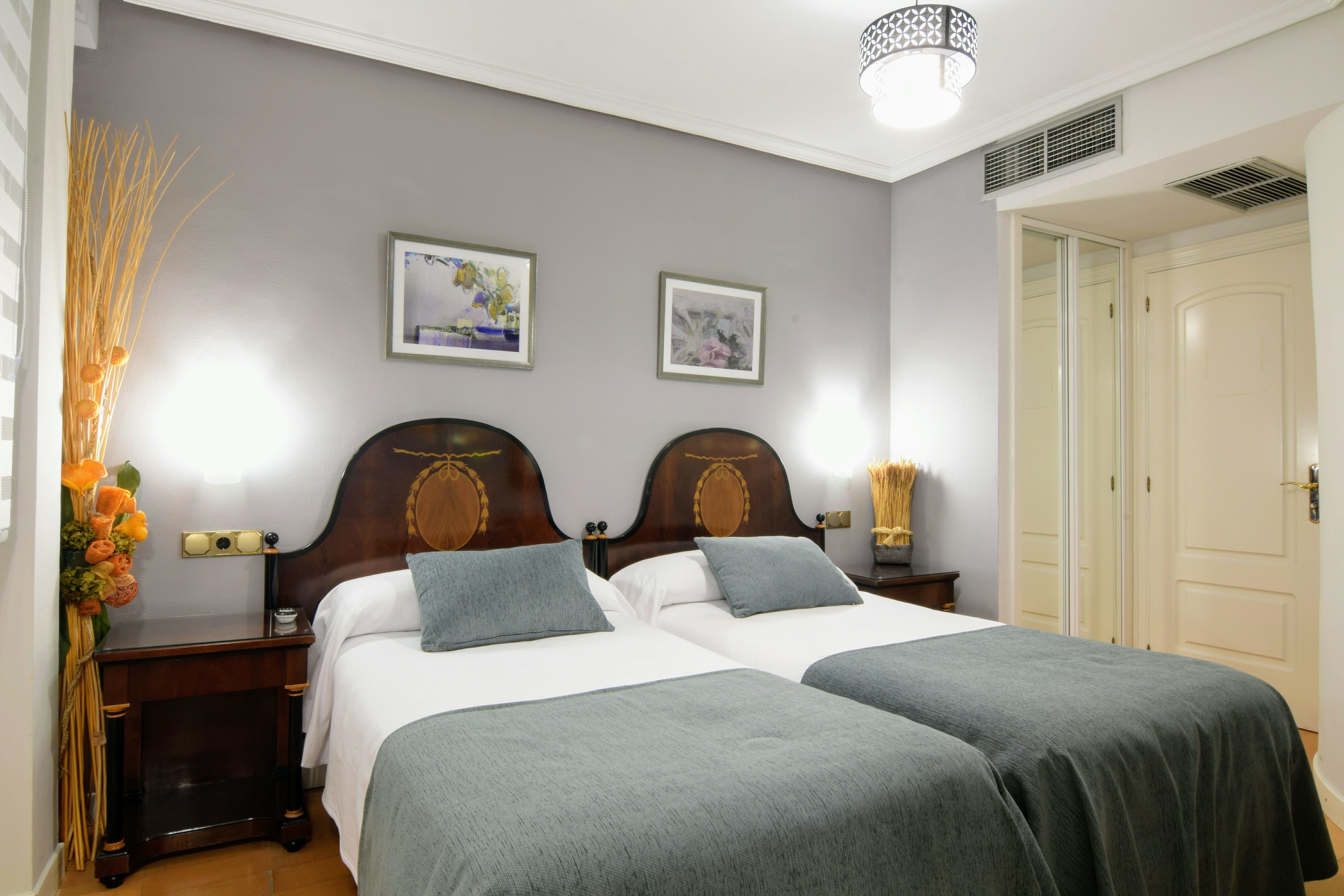 Una habitación de hotel con dos camas, una mesita de noche, una lámpara y una puerta.