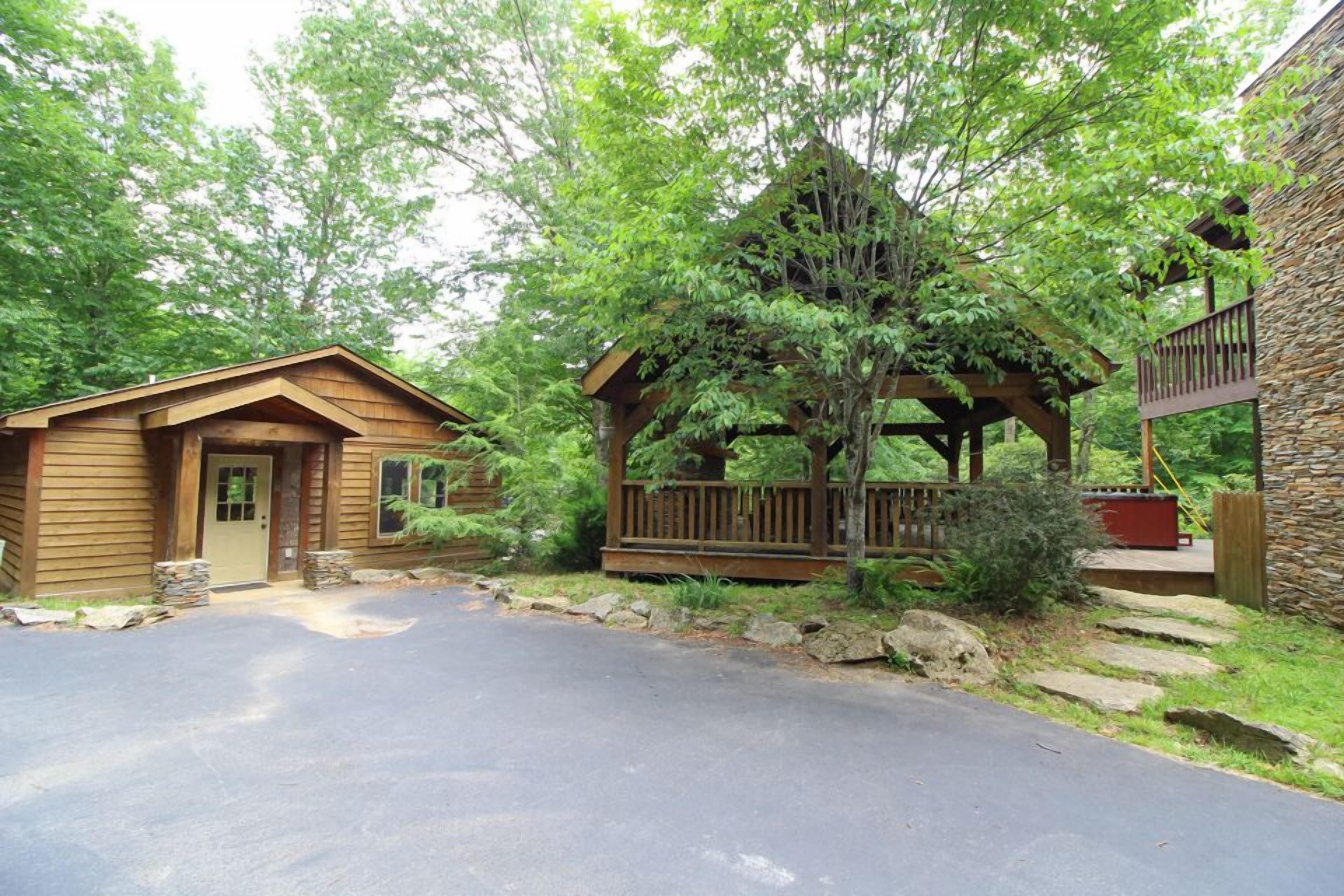 A cabin with a wooden exterior, a stone porch, and a stone wall.