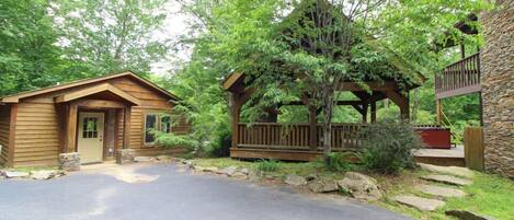 A cabin with a wooden exterior, a stone porch, and a stone wall.