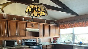 A kitchen with wooden cabinets, a microwave, a stove, and a large island with a built-in dishwasher. - The Charter House formally known as The Charter Room. A 3 bedroom house for rent (Ocracoke)