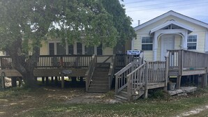 A two-story building with a porch and a staircase leading to the upper level. - The Charter House formally known as The Charter Room. A 3 bedroom house for rent (Ocracoke)