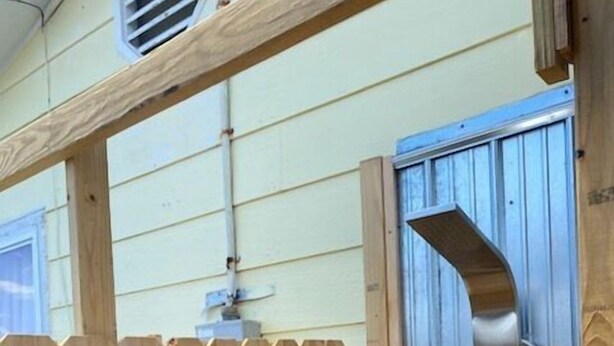 A wooden fence with a metal gate, a wooden post, and a metal vent. - The Charter House formally known as The Charter Room. A 3 bedroom house for rent (Ocracoke)