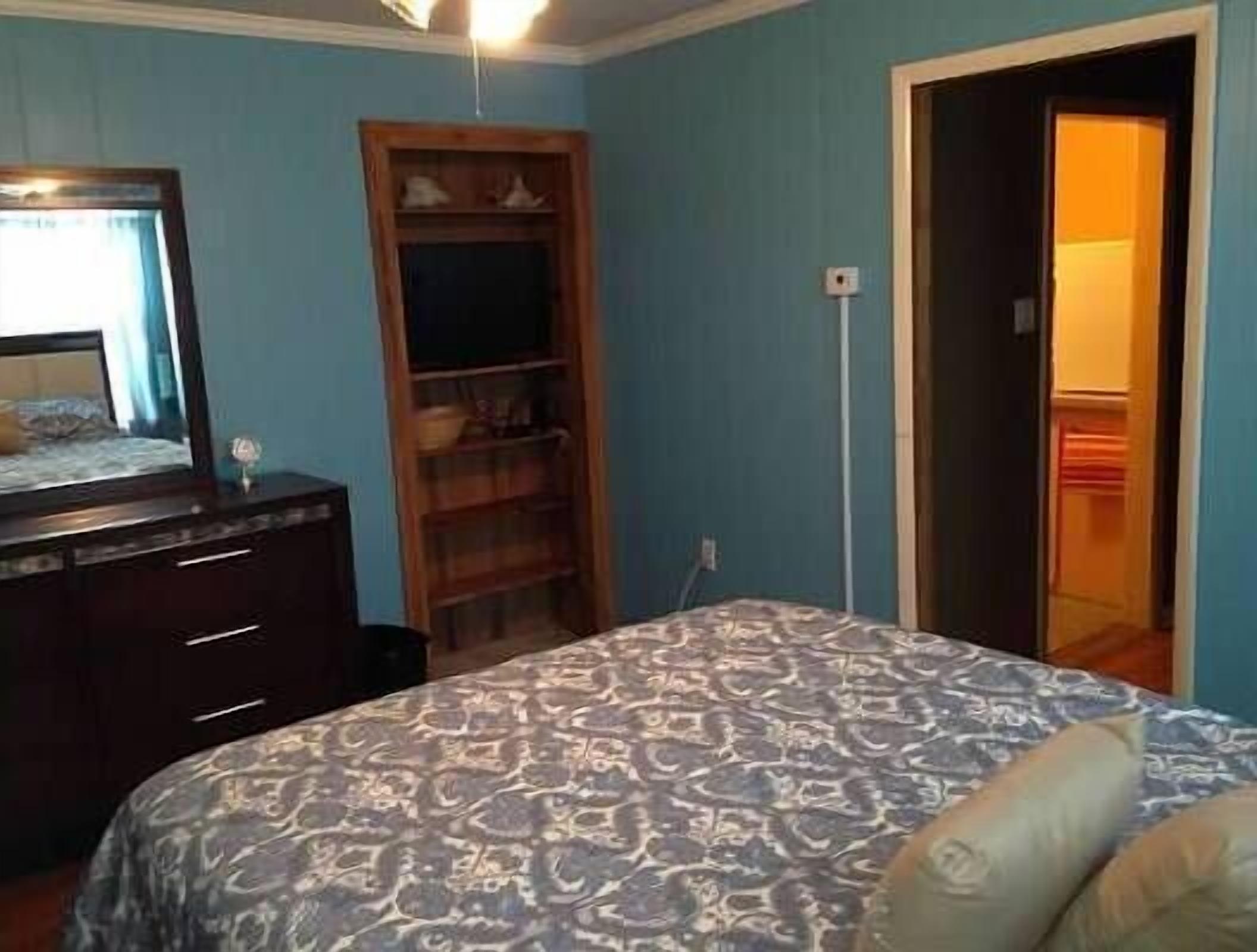 A bedroom with a bed, dresser, and a wardrobe.