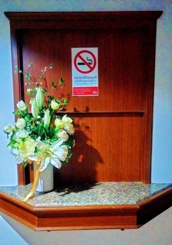 A wooden cabinet with a no-smoking sign and a bouquet of white flowers. - China Garden Hotel (Hat Yai)
