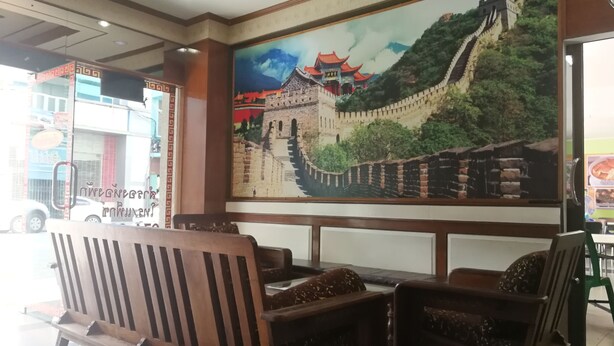 Quarto com bancos de madeira e um grande mural da Grande Muralha da China.
