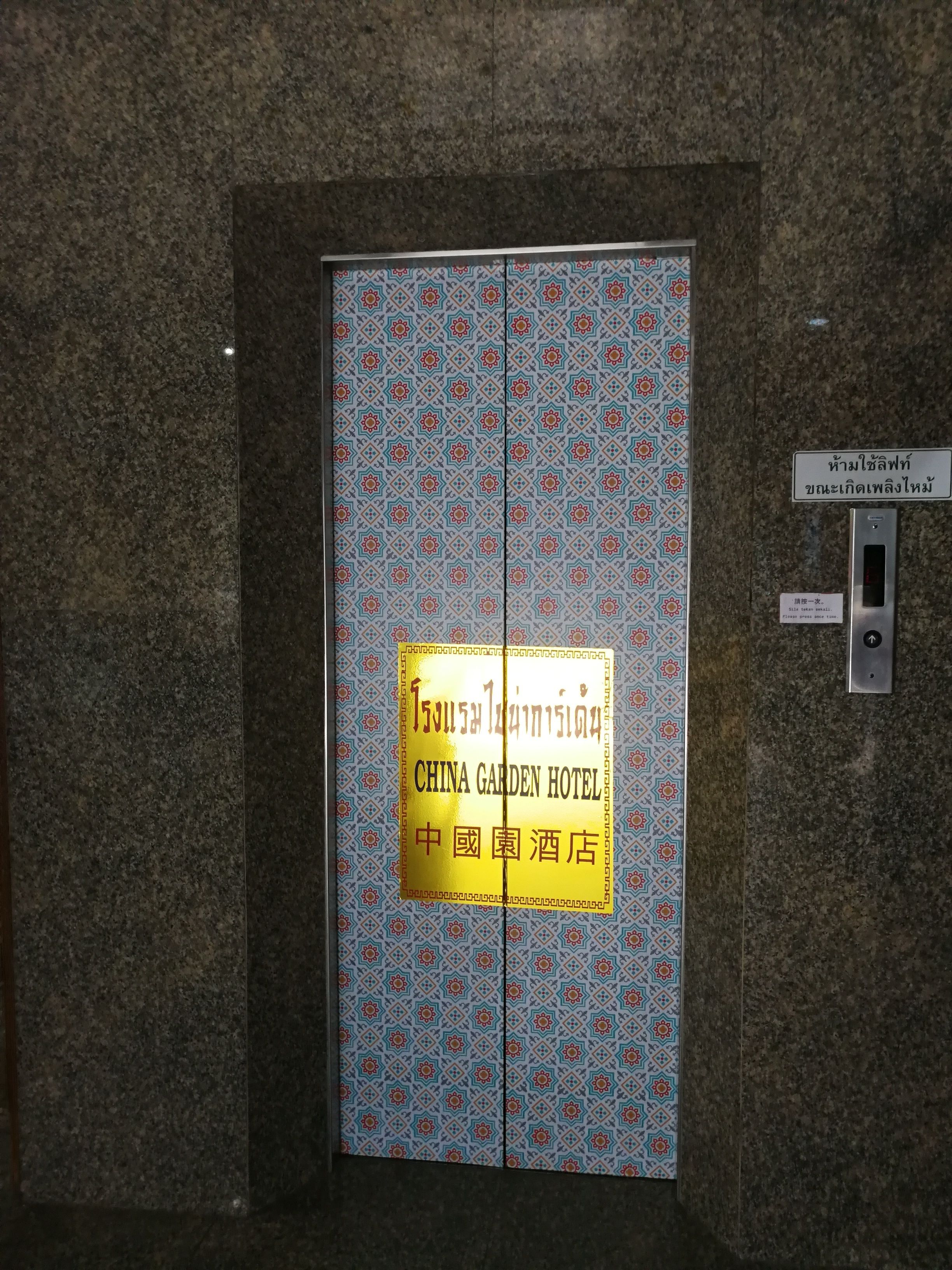 A hotel entrance with a patterned door and a sign indicating the name "China Garden Hotel".