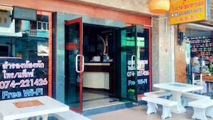 Entrada de hotel com porta de vidro, placa oferecendo Wi-Fi gratuito e área de estar externa.