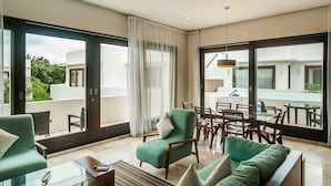 Una habitación de hotel moderna con balcón, zona de comedor y vistas a la piscina.