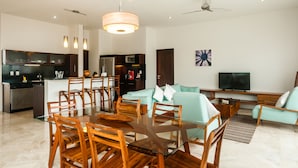 Una sala de estar moderna con comedor, cocina y televisor.