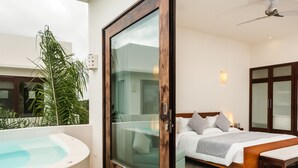 Un dormitorio con cama, mesita de noche y un ventanal grande.