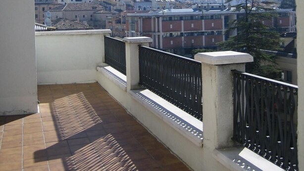 Un balcon donnant sur la ville et une colline.