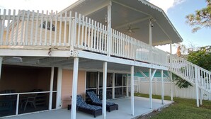 Una casa de dos pisos con un porche cubierto, un balcón y una escalera.